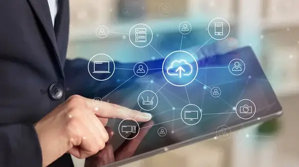 Hands tapping a tablet with cloud network icons